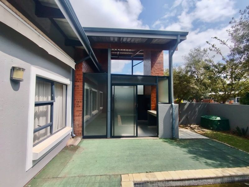 Covered patio area featuring a built-in braai, sliding glass doors, and direct access to the swimming pool, offering a functional outdoor entertainment space.