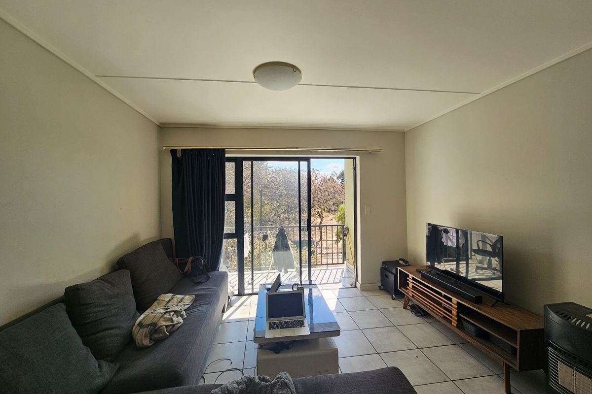 A living room featuring tiled flooring and a sliding glass door that provides access to an outdoor balcony area.