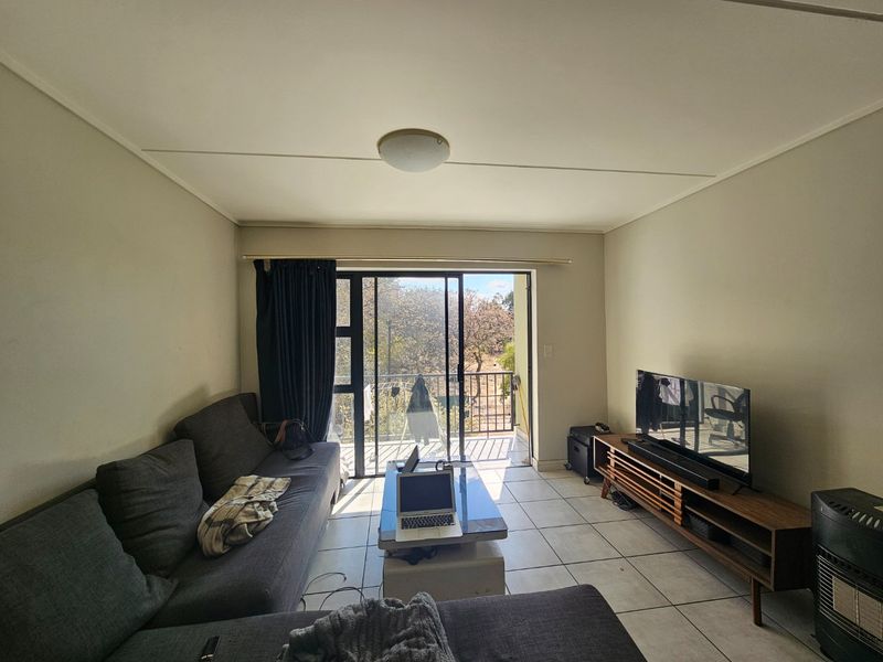 A living room featuring tiled flooring and a sliding glass door that provides access to an outdoor balcony area.