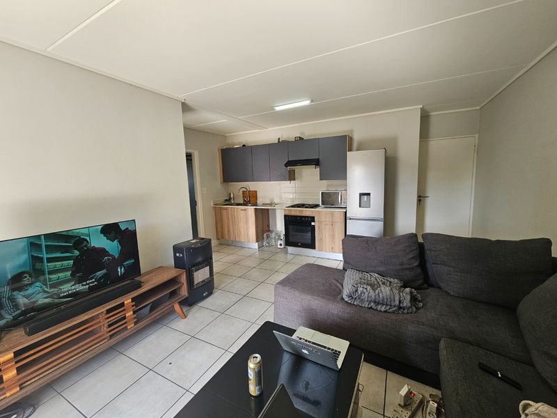 Open-plan living area featuring a functional kitchen with built-in cabinetry, oven, hob, and extractor fan, seamlessly connected to the lounge space.