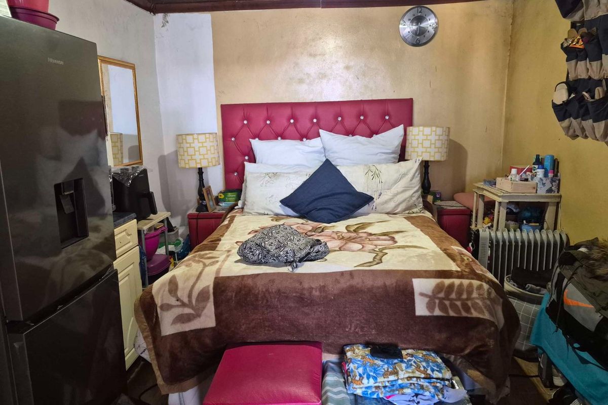 A bedroom featuring a timber ceiling and painted walls showing signs of wear and surface deterioration.