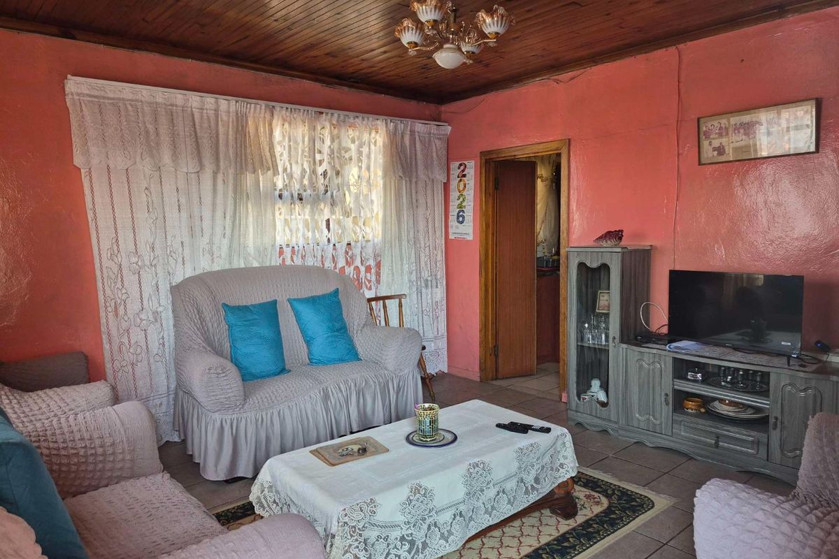 A living room featuring tiled flooring and a timber tongue and groove ceiling, offering a dated aesthetic with potential for modernization.