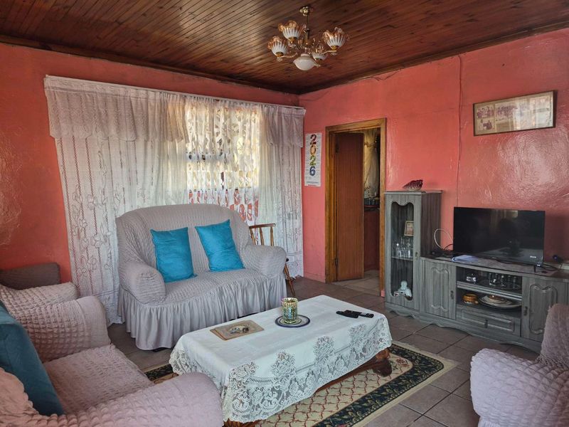 A living room featuring tiled flooring and a timber tongue and groove ceiling, offering a dated aesthetic with potential for modernization.