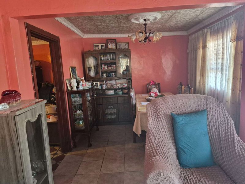 A dining area featuring tiled flooring, a decorative ceiling rose, and patterned ceiling tiles, offering a traditional layout ready for modern updates.