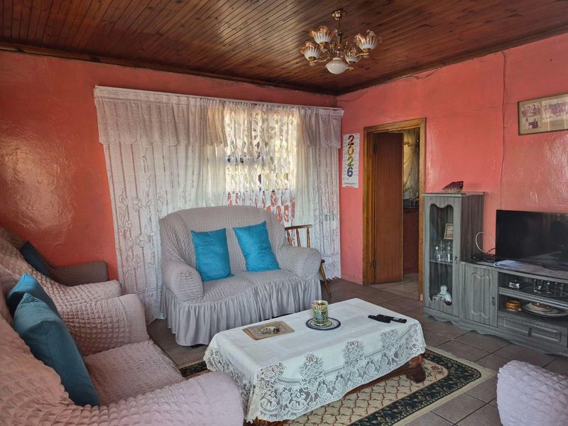 A living room featuring a timber tongue and groove ceiling and ceramic tiled flooring, offering a dated aesthetic ready for modernization.