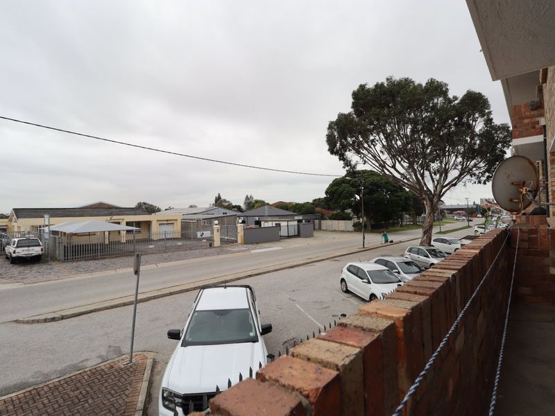 View from an elevated balcony overlooking a suburban street, parking area, and surrounding residential properties.