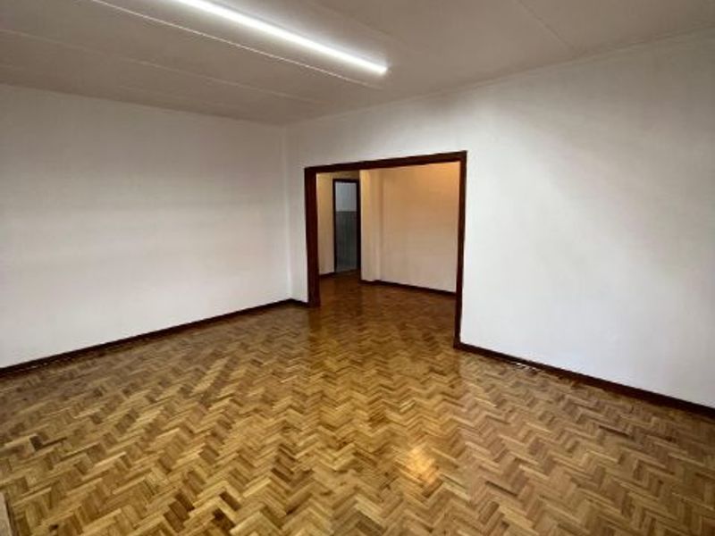 An empty living area featuring polished herringbone parquet flooring and neutral walls, providing a versatile space for interior design.