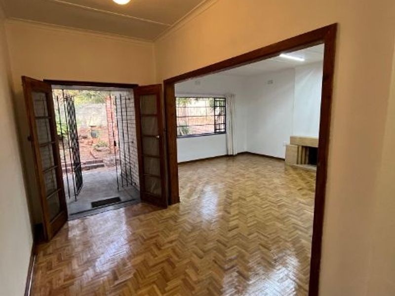 Spacious living area featuring polished herringbone parquet flooring, a built-in fireplace, and direct access to the garden through classic french doors.
