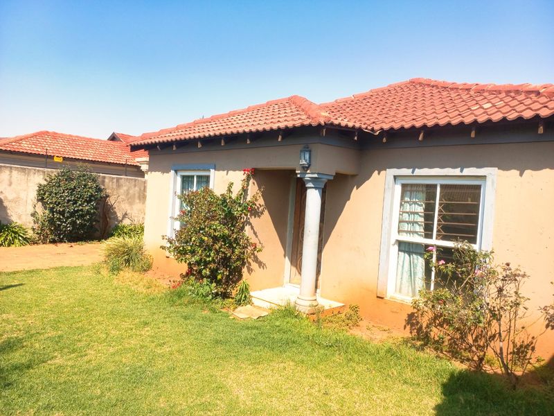 Front view of a single-story house featuring a terracotta tiled roof, a covered entrance with a decorative column, and security-fitted windows.