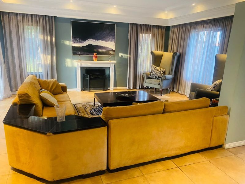 A comfortable living room featuring a central fireplace with a mantelpiece, tiled flooring, and recessed ceiling lighting, creating a warm and inviting atmosphere.
