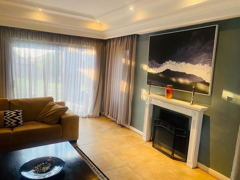 A well-maintained living room featuring a classic fireplace with a mantelpiece, recessed ceiling lighting, crown molding, and large sliding glass doors leading outdoors.