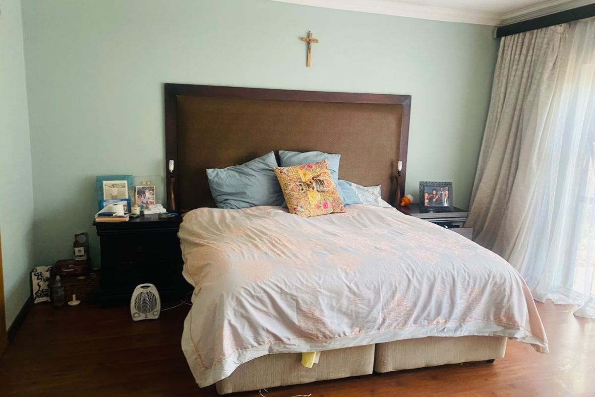 A well-maintained bedroom featuring laminate flooring, crown molding, and a sliding glass door providing natural light.