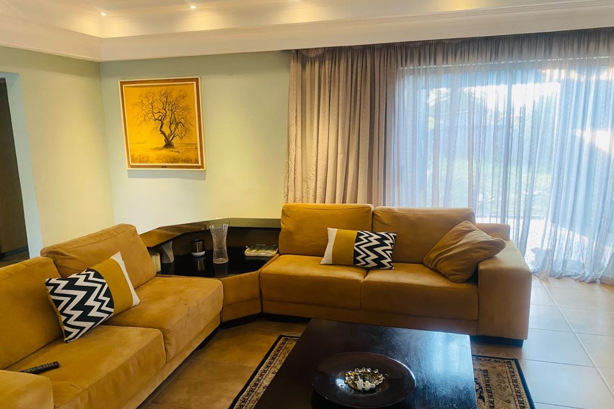 A comfortable living room featuring tiled floors, recessed ceiling lighting, crown molding, and a large sliding glass door leading to the exterior.