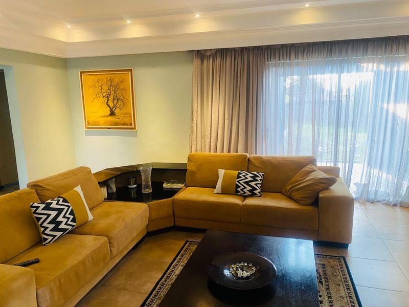 A comfortable living room featuring tiled floors, recessed ceiling lighting, crown molding, and a large sliding glass door leading to the exterior.