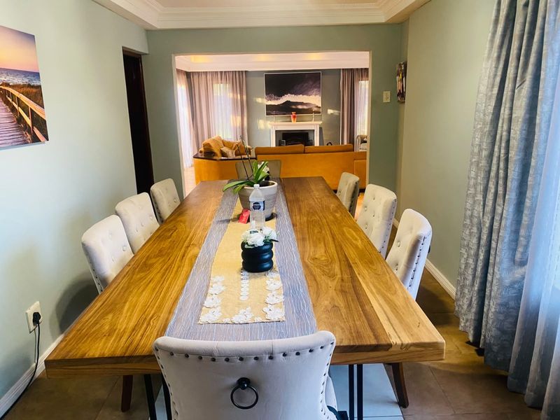 A spacious dining room featuring a cove ceiling and tiled flooring, with an open-plan flow leading into the adjacent living area.
