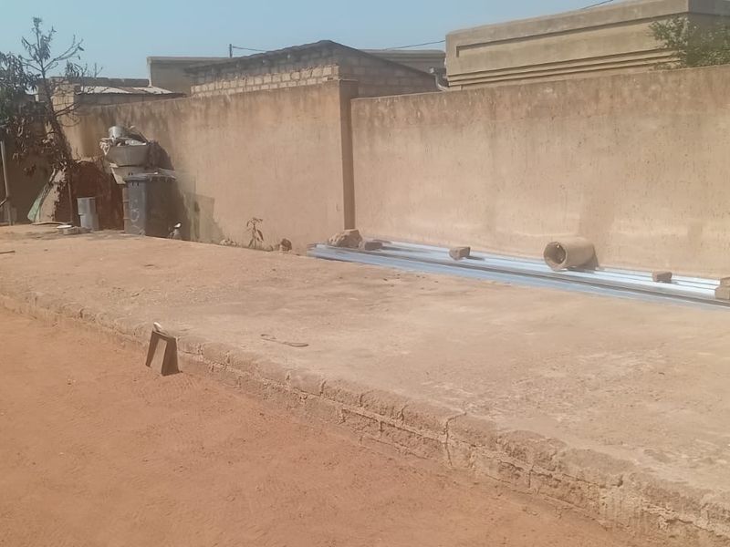 A rear outdoor area featuring a concrete slab foundation and a perimeter boundary wall, offering potential for landscaping or patio development.