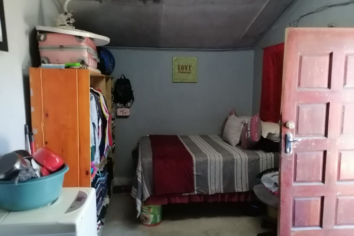 A compact bedroom featuring a timber panel door and visible ceiling damage, requiring maintenance and cosmetic updates to improve the living space.