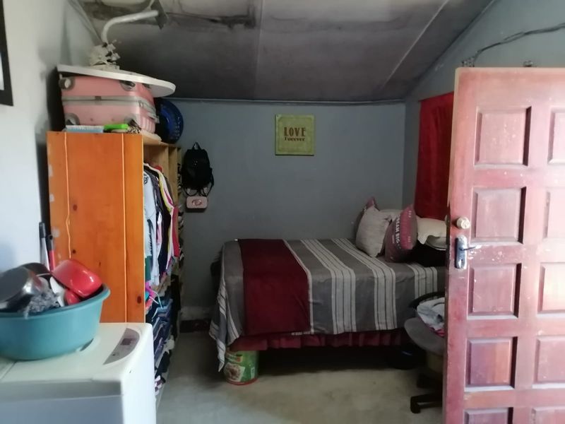 A compact bedroom featuring a timber panel door and visible ceiling damage, requiring maintenance and cosmetic updates to improve the living space.