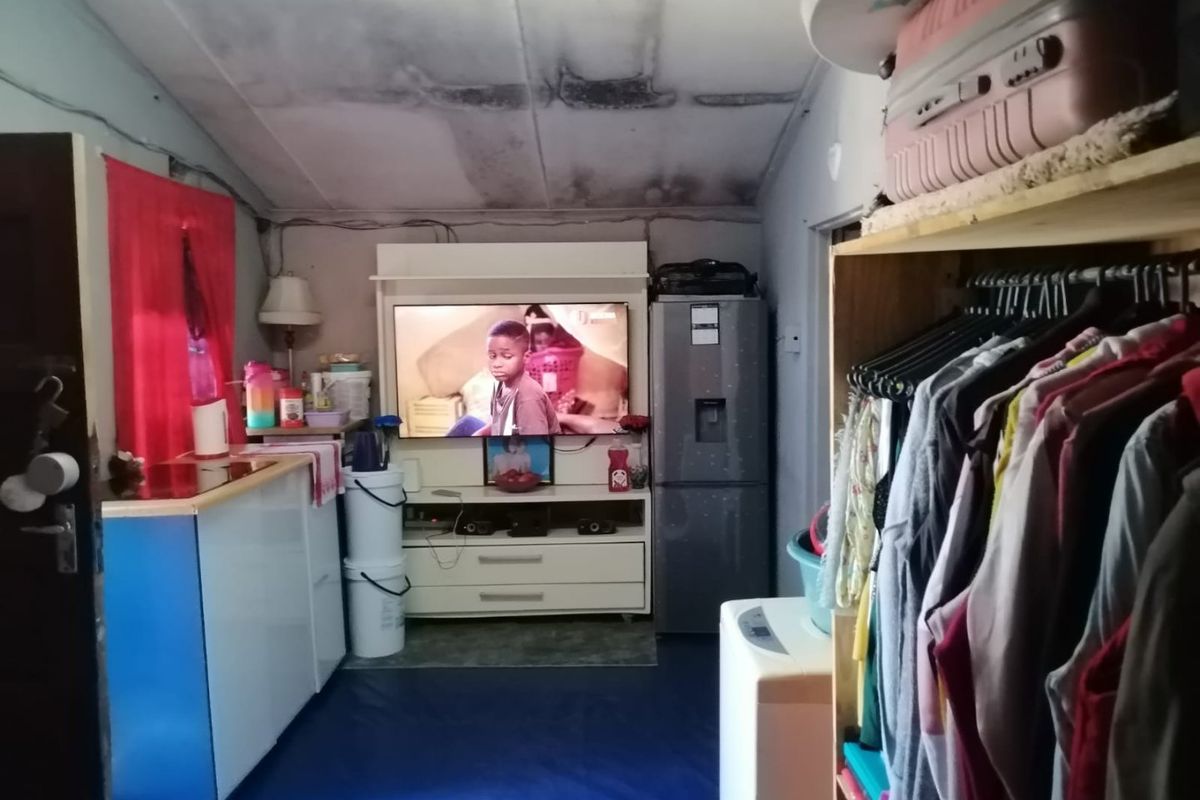 Compact open-plan living and kitchen area showing signs of significant ceiling water damage and general wear, requiring maintenance and cosmetic updates.