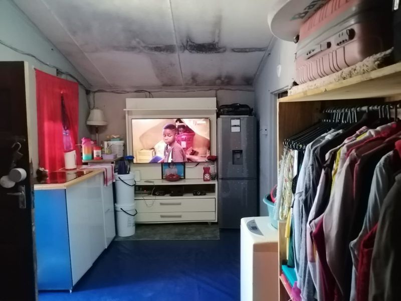 Compact open-plan living and kitchen area showing signs of significant ceiling water damage and general wear, requiring maintenance and cosmetic updates.