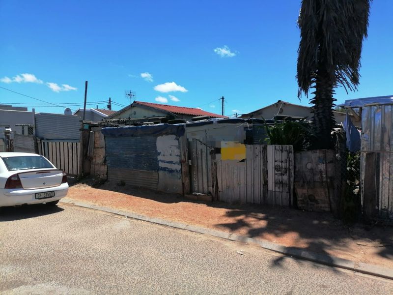 Front view of the property showing the street-facing boundary fence and entrance gate constructed from corrugated metal and timber materials.