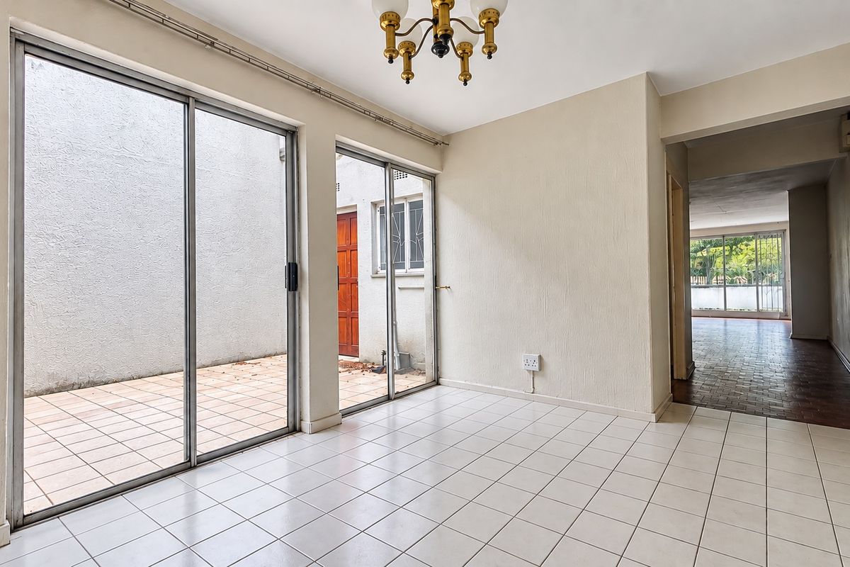 An empty living area featuring tiled flooring and large sliding glass doors that provide access to an outdoor patio space.