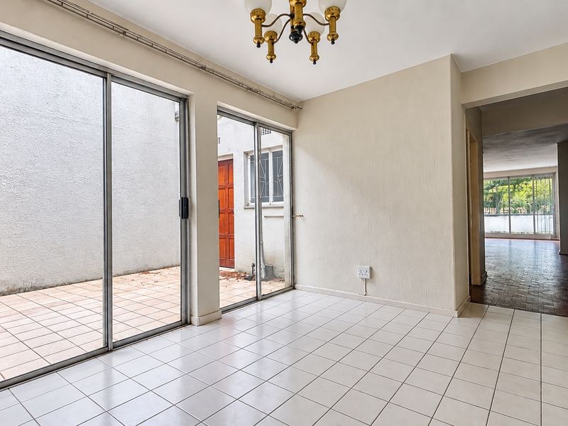 An empty living area featuring tiled flooring and large sliding glass doors that provide access to an outdoor patio space.