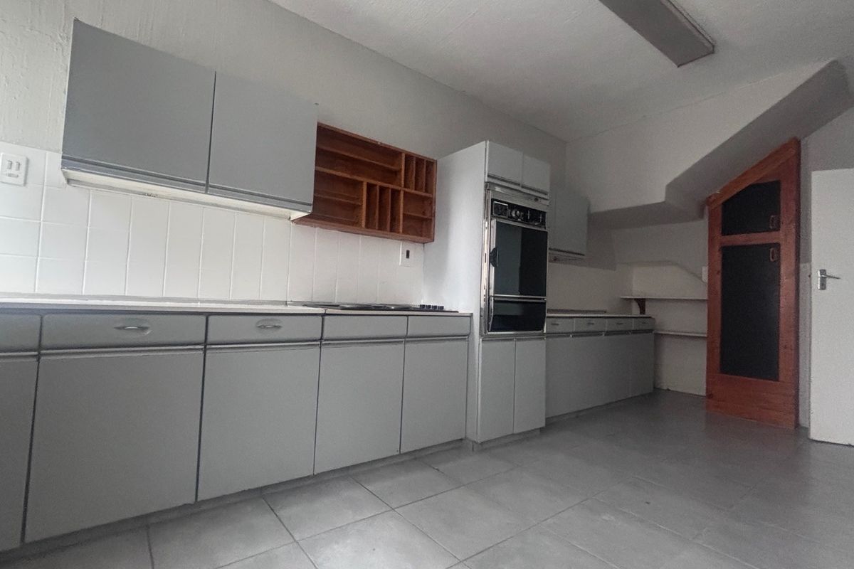 A functional kitchen featuring built-in cabinetry, a tiled backsplash, and integrated oven and hob, offering a blank canvas for modern updates.