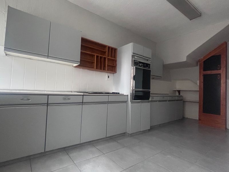 A functional kitchen featuring built-in cabinetry, a tiled backsplash, and integrated oven and hob, offering a blank canvas for modern updates.