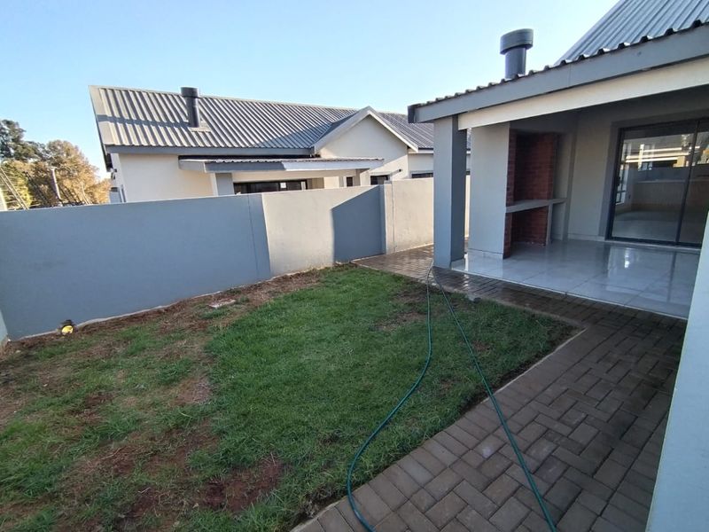 Covered patio area featuring a built-in braai, tiled flooring, and direct access to a small private garden with a boundary wall.