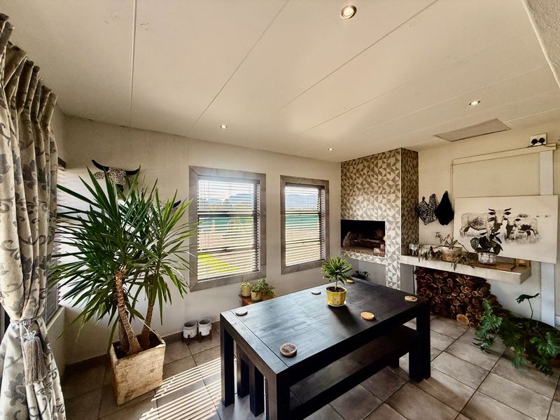 A cozy living area featuring a built-in fireplace with decorative tiling, tiled flooring, and natural light through venetian blinds.