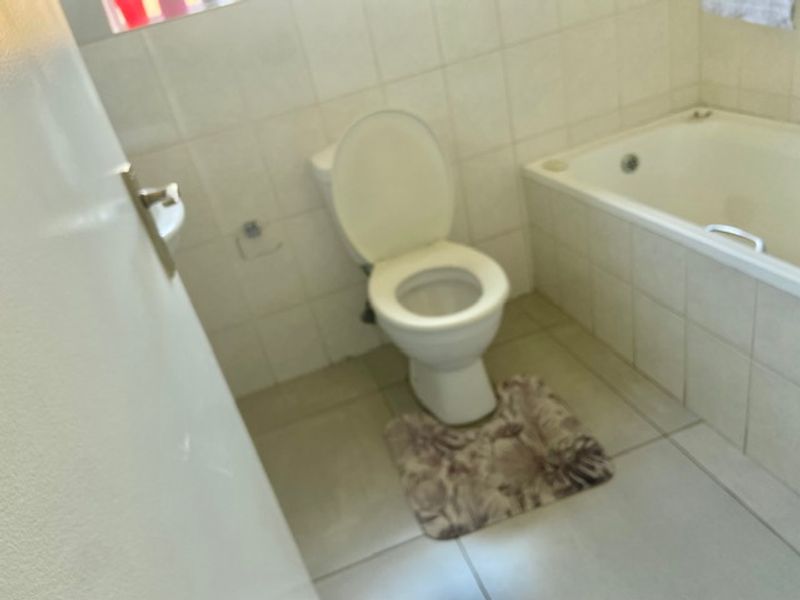 A functional bathroom featuring a standard toilet and a built-in bathtub with tiled walls and flooring.