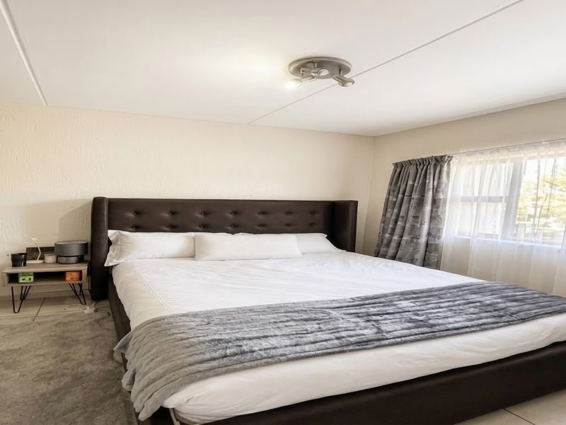 A well-maintained bedroom featuring neutral walls, tiled flooring, and a built-in wardrobe, offering a clean and functional living space.