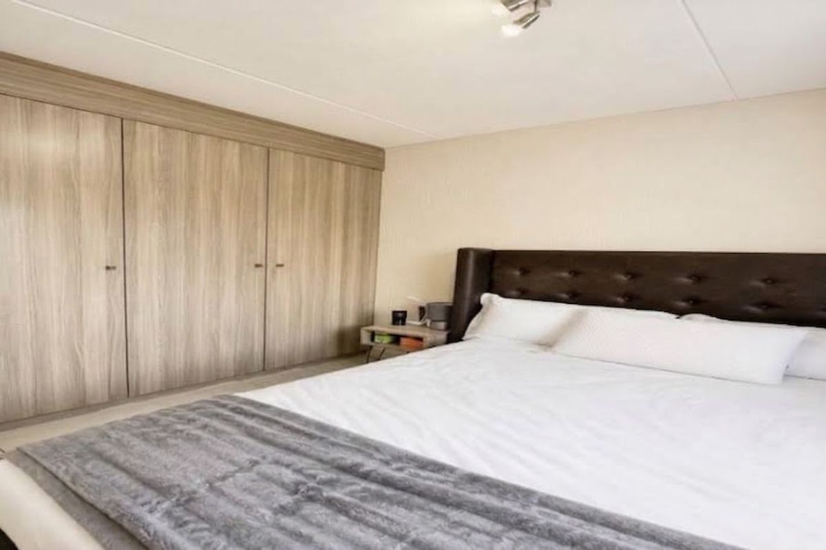 A well-maintained bedroom featuring extensive built-in wooden cabinetry and neutral wall finishes, providing ample storage and a clean, functional living space.