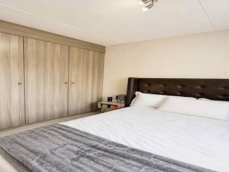 A well-maintained bedroom featuring extensive built-in wooden cabinetry and neutral wall finishes, providing ample storage and a clean, functional living space.