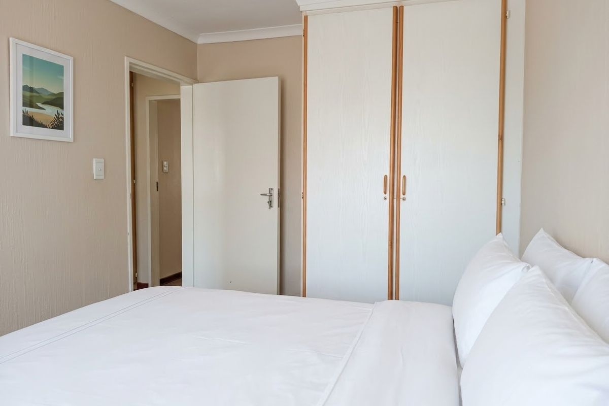 A bedroom featuring a built-in wardrobe with white doors and neutral wall finishes, providing a clean and functional sleeping space.