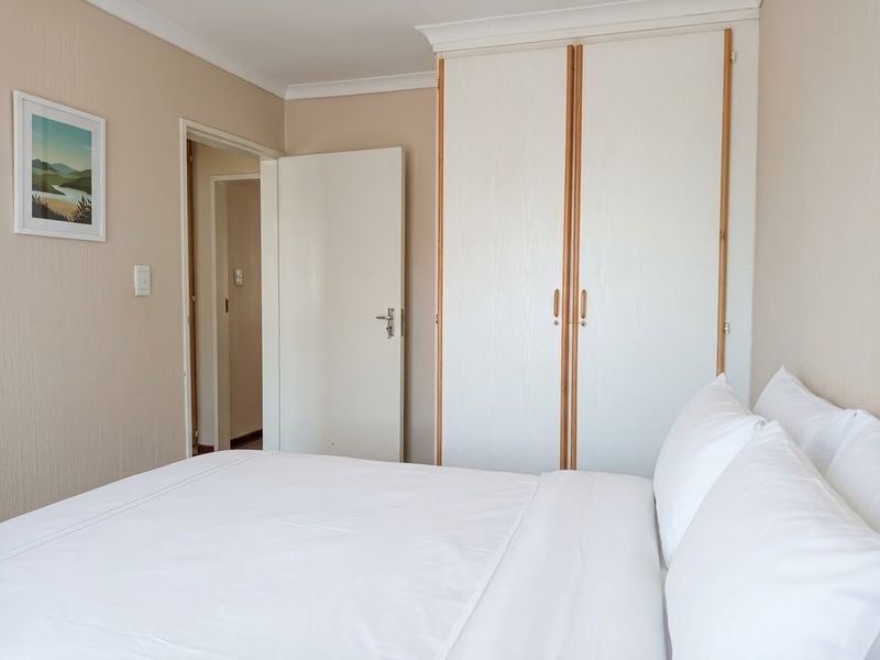 A bedroom featuring a built-in wardrobe with white doors and neutral wall finishes, providing a clean and functional sleeping space.