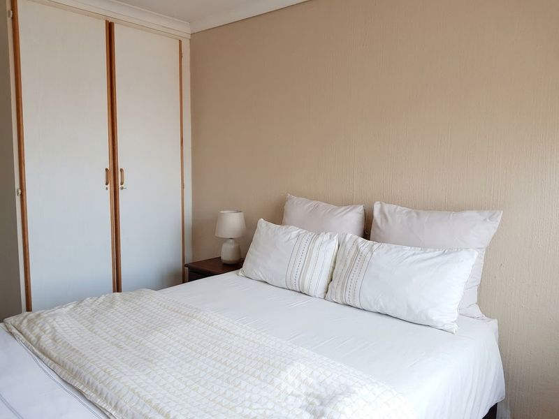 A bedroom featuring a built-in wardrobe with white doors and neutral wall finishes.
