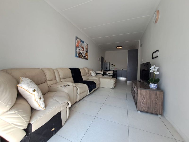 Open plan living area featuring tiled flooring and a compact kitchen space with built-in cabinetry and sink.