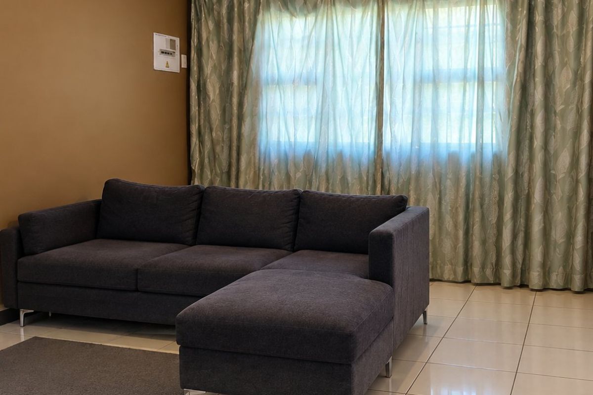 A living room featuring neutral tiled flooring and a wall-mounted electrical distribution board, providing a functional and well-lit space.
