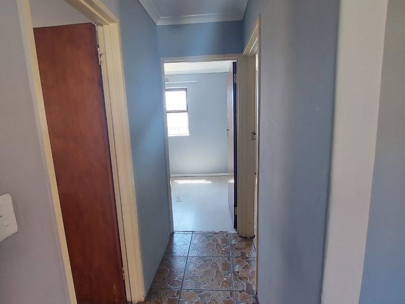 A functional hallway connecting multiple rooms, featuring tiled flooring and neutral wall paint, providing access to the interior living spaces.