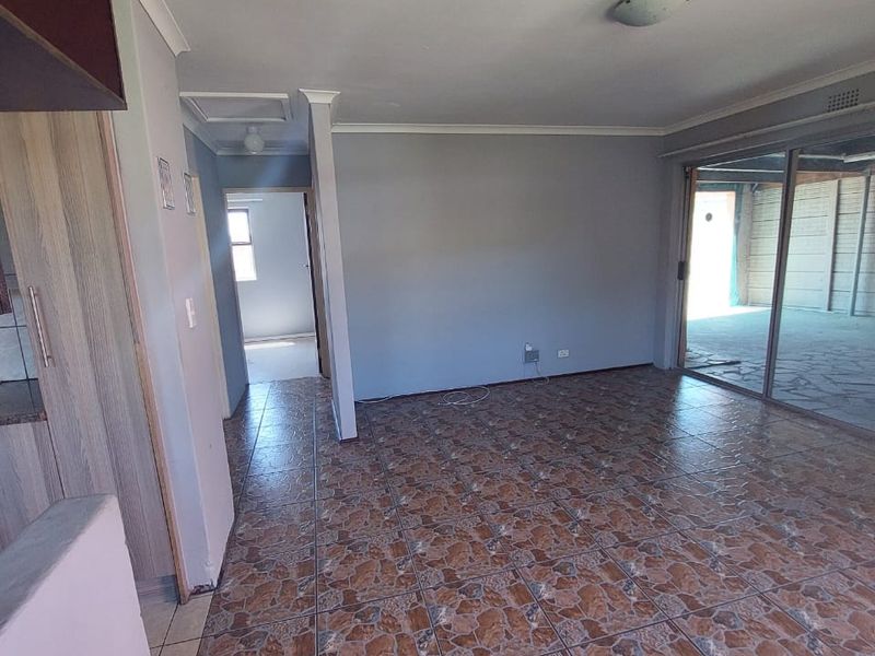 An empty open-plan living area featuring tiled flooring, built-in cabinetry, and a large sliding glass door leading to an outdoor space.