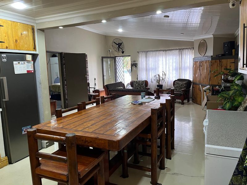 Spacious open-plan living and dining area featuring tiled flooring, recessed lighting, and a classic tongue and groove ceiling design.