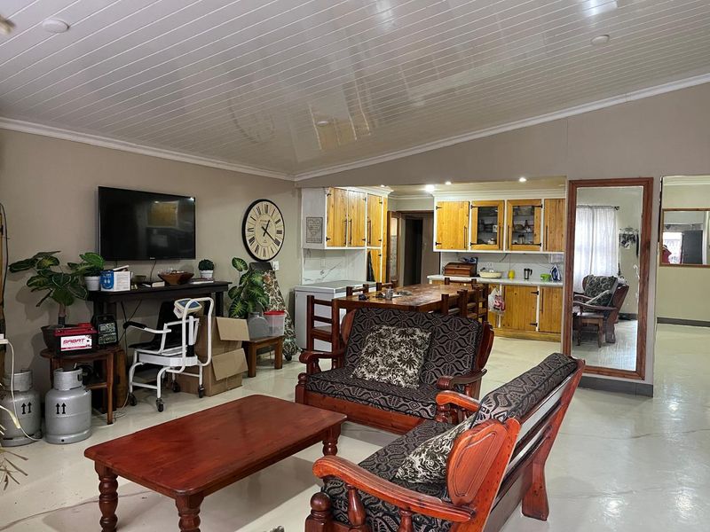 Open plan living and kitchen area featuring wooden cabinetry, a tongue and groove ceiling, and neutral wall tones.
