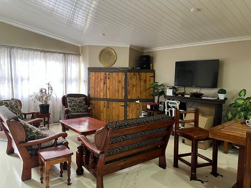 A living room featuring a vaulted tongue and groove ceiling and tiled flooring, providing a spacious area for relaxation.