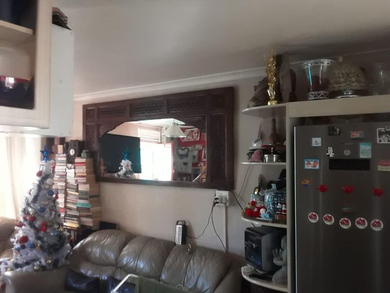 A living area featuring a built-in shelving unit and a decorative wall-mounted mirror, providing a functional space for storage and display.