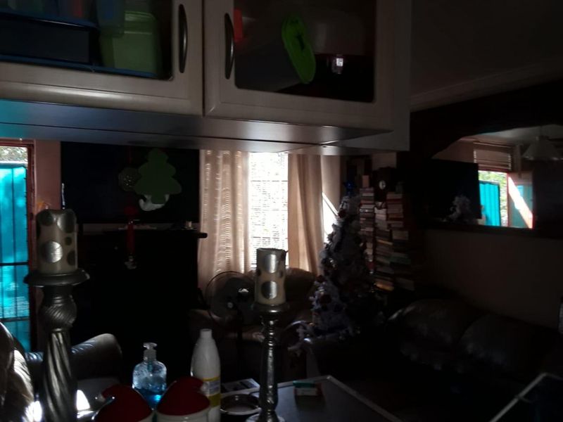 A dimly lit living room area featuring built-in cabinetry and an architectural archway, providing a functional space with potential for modernization.