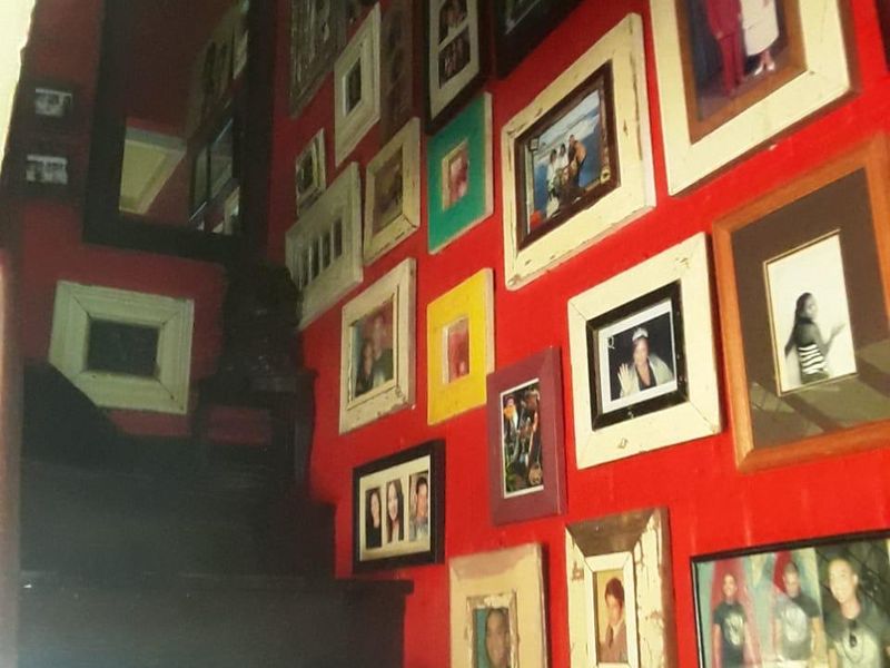 A staircase area featuring a bold red wall decorated with numerous framed photographs.
