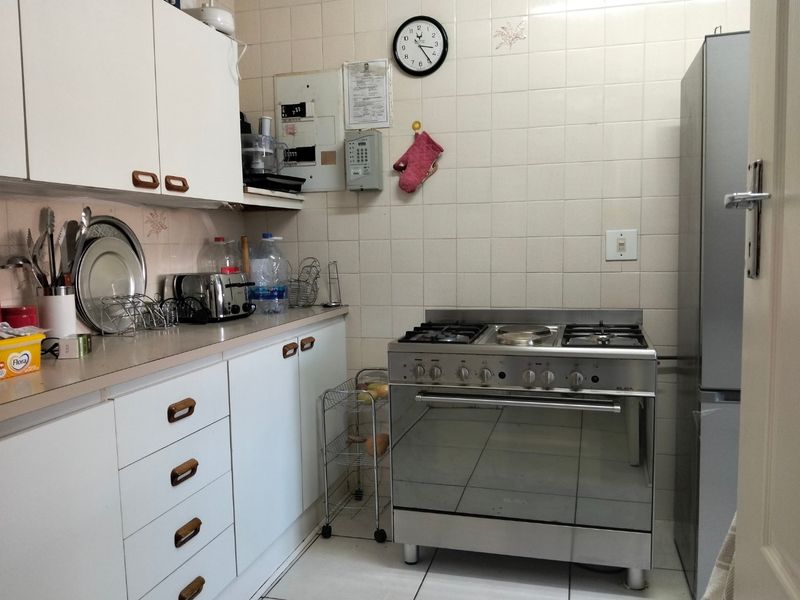 A functional kitchen featuring white cabinetry, a stainless steel gas stove, tiled backsplash, and tiled flooring, offering a practical layout for daily cooking.