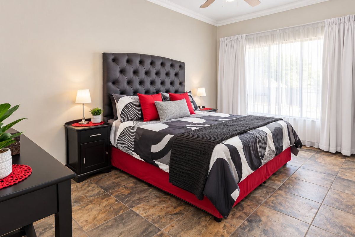 A well-maintained bedroom featuring neutral wall tones, durable tiled flooring, and a ceiling fan, offering a clean and functional living space.